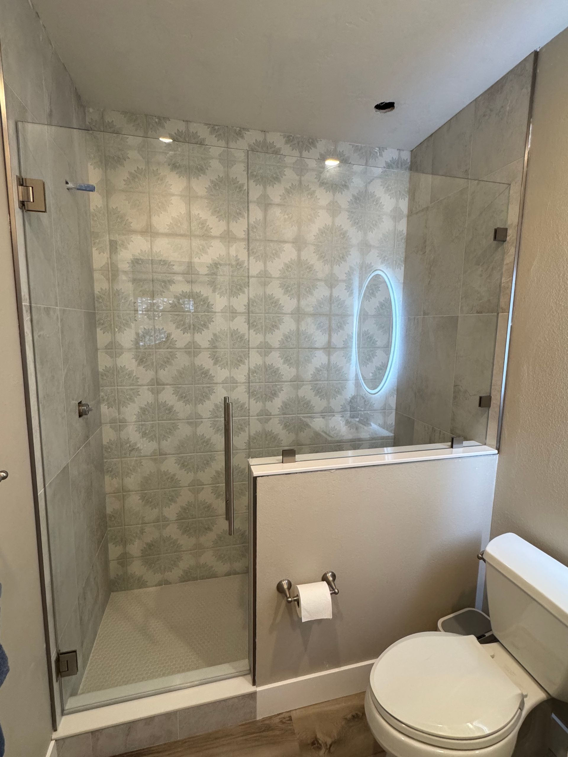 A bathroom with a toilet , shower and mirror.