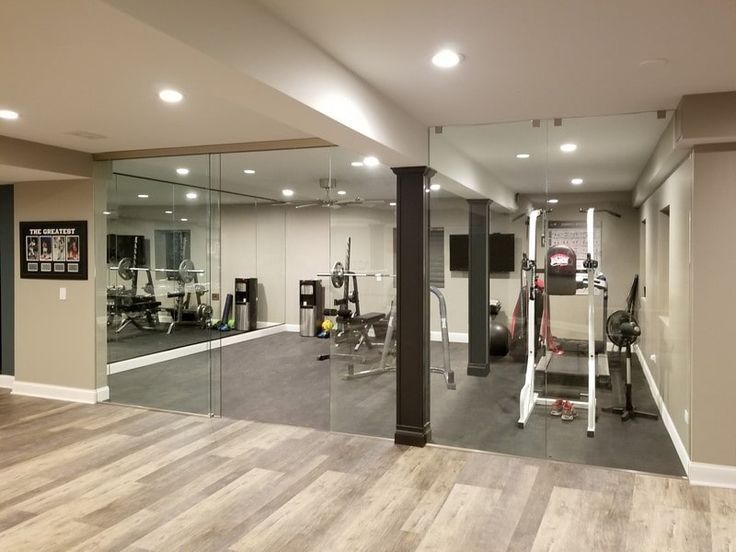 Home gym with wood floor, exercise equipment, and glass-walled workout space.