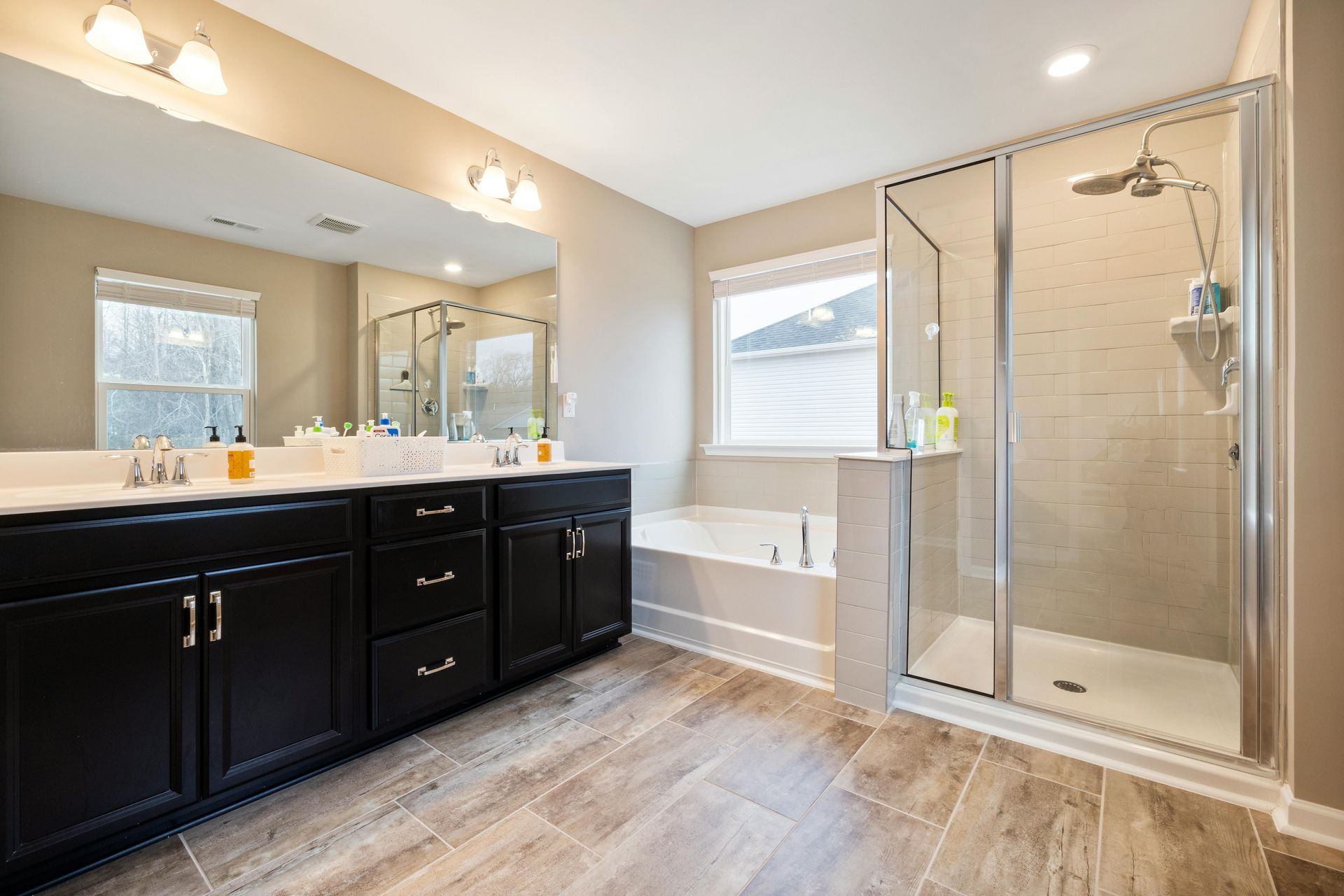 A bathroom with two sinks , a tub , and a walk in shower.