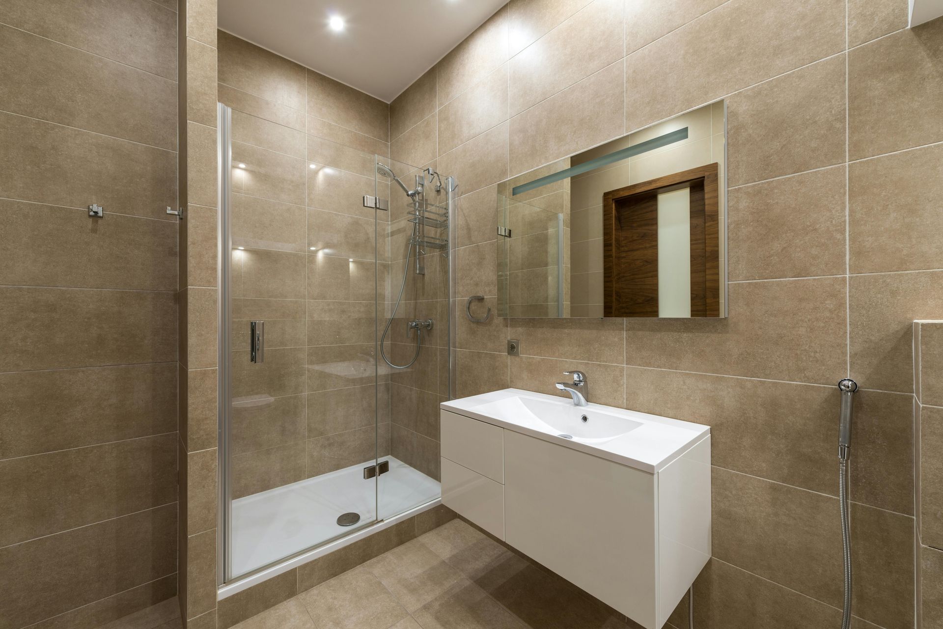 A bathroom with a sink , mirror and walk in shower.