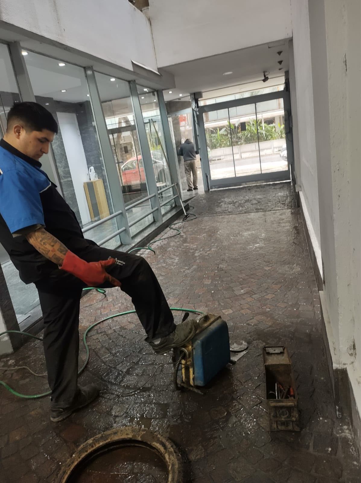 Un trabajador usa una herramienta eléctrica para pulir el suelo mojado de un pasillo interior