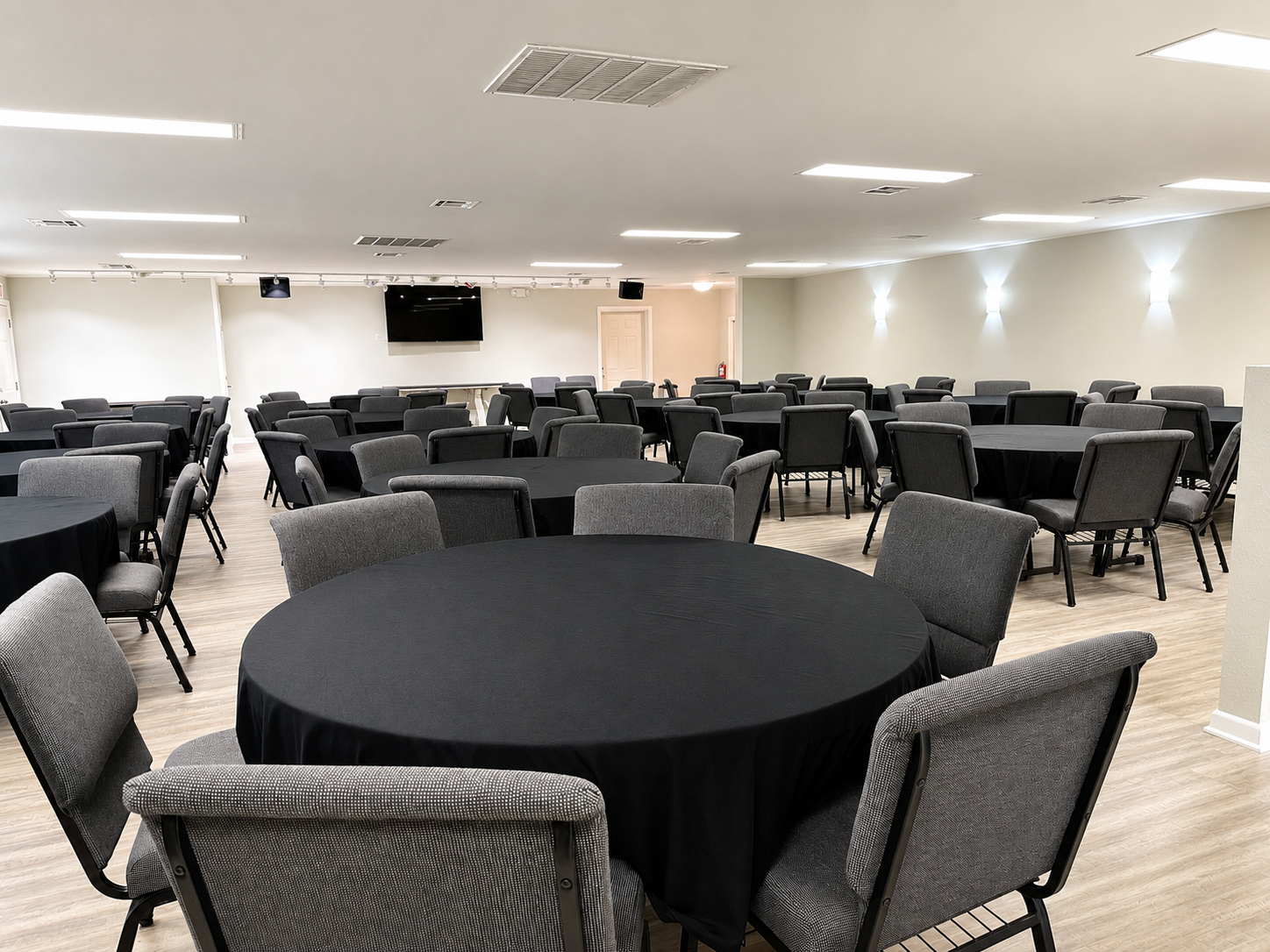Empty room with round tables and gray chairs under bright ceiling lights