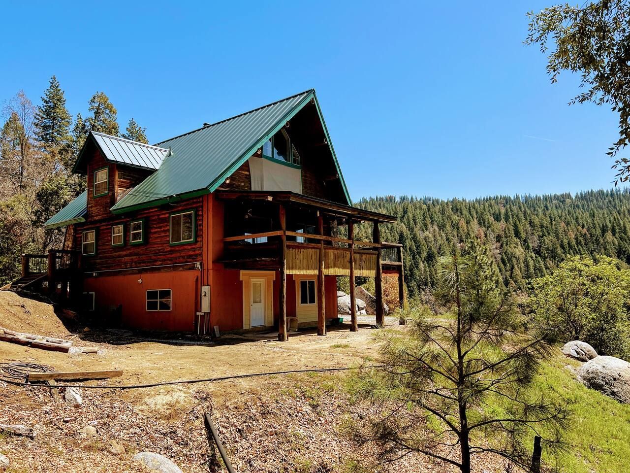 Exterior view of the Italian Bar Cabin from a far away angle with surrounding pines and mountains.
