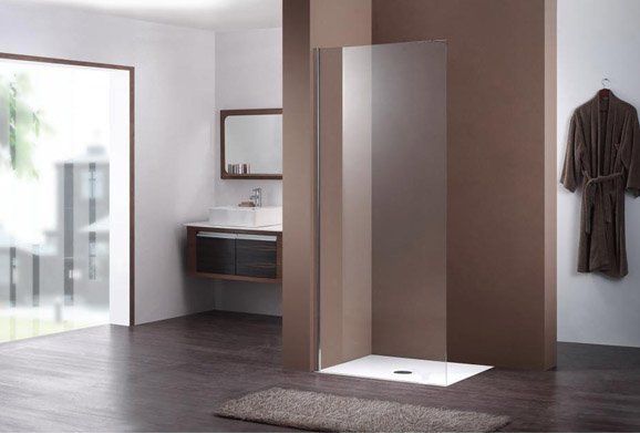 A walk-in shower with a glass screen and white tray in a modern, dark-toned bathroom with a floating vanity.