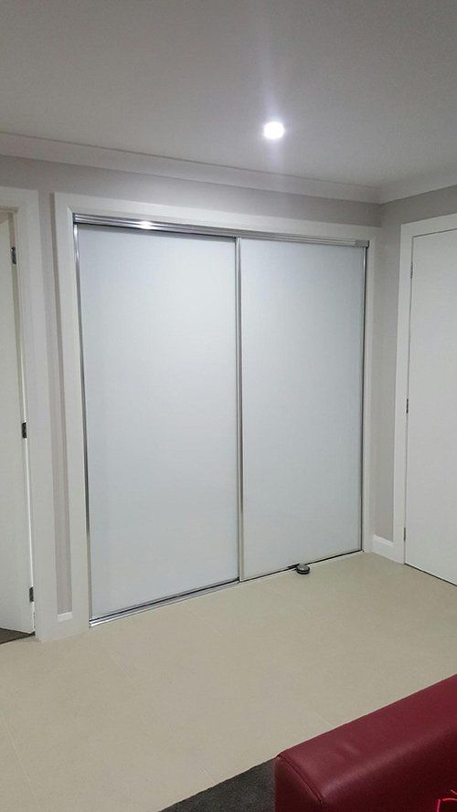 White sliding closet doors with silver frames set in a neutral-toned room.