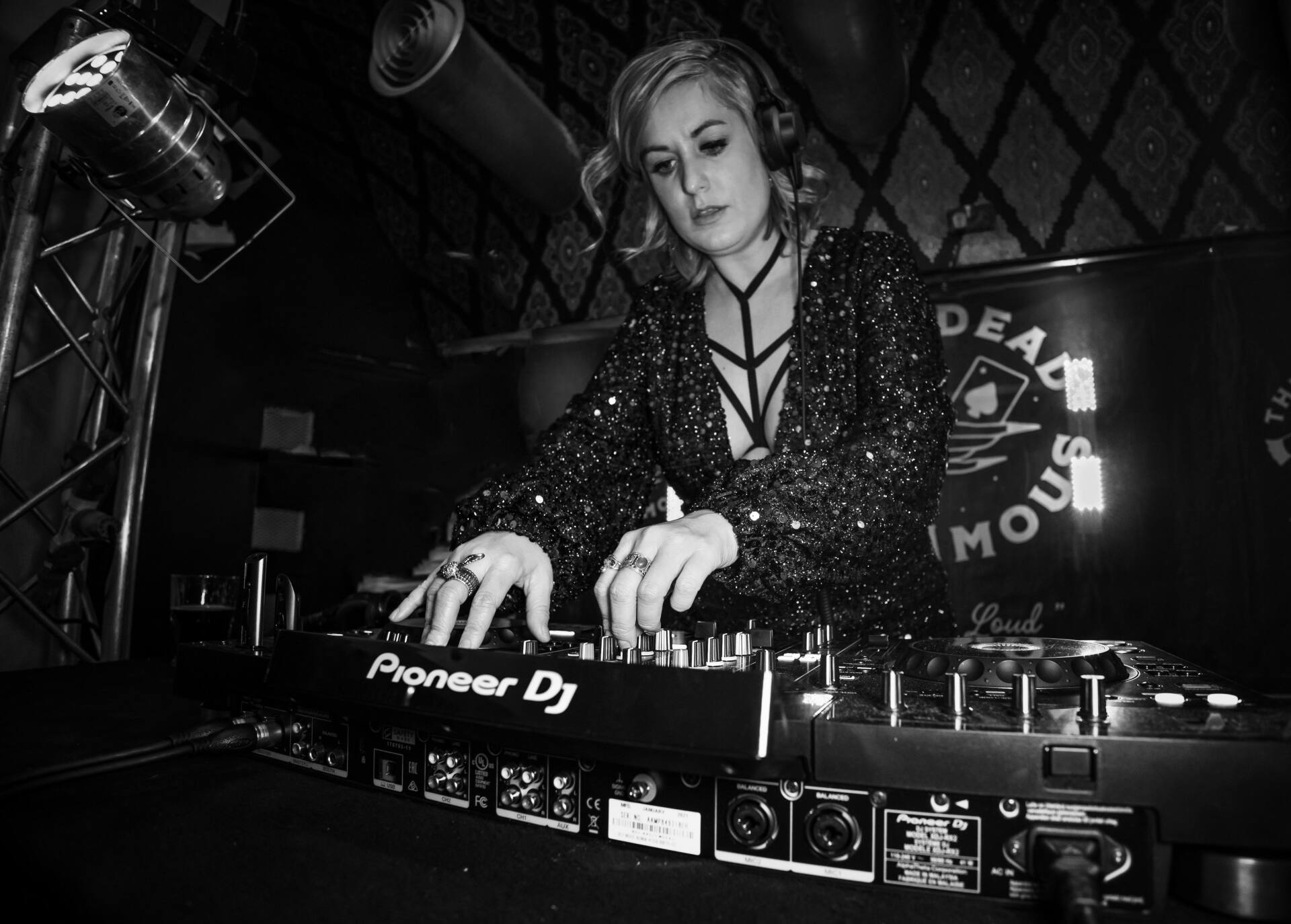 A woman is playing music on a pioneer dj mixer in a black and white photo.