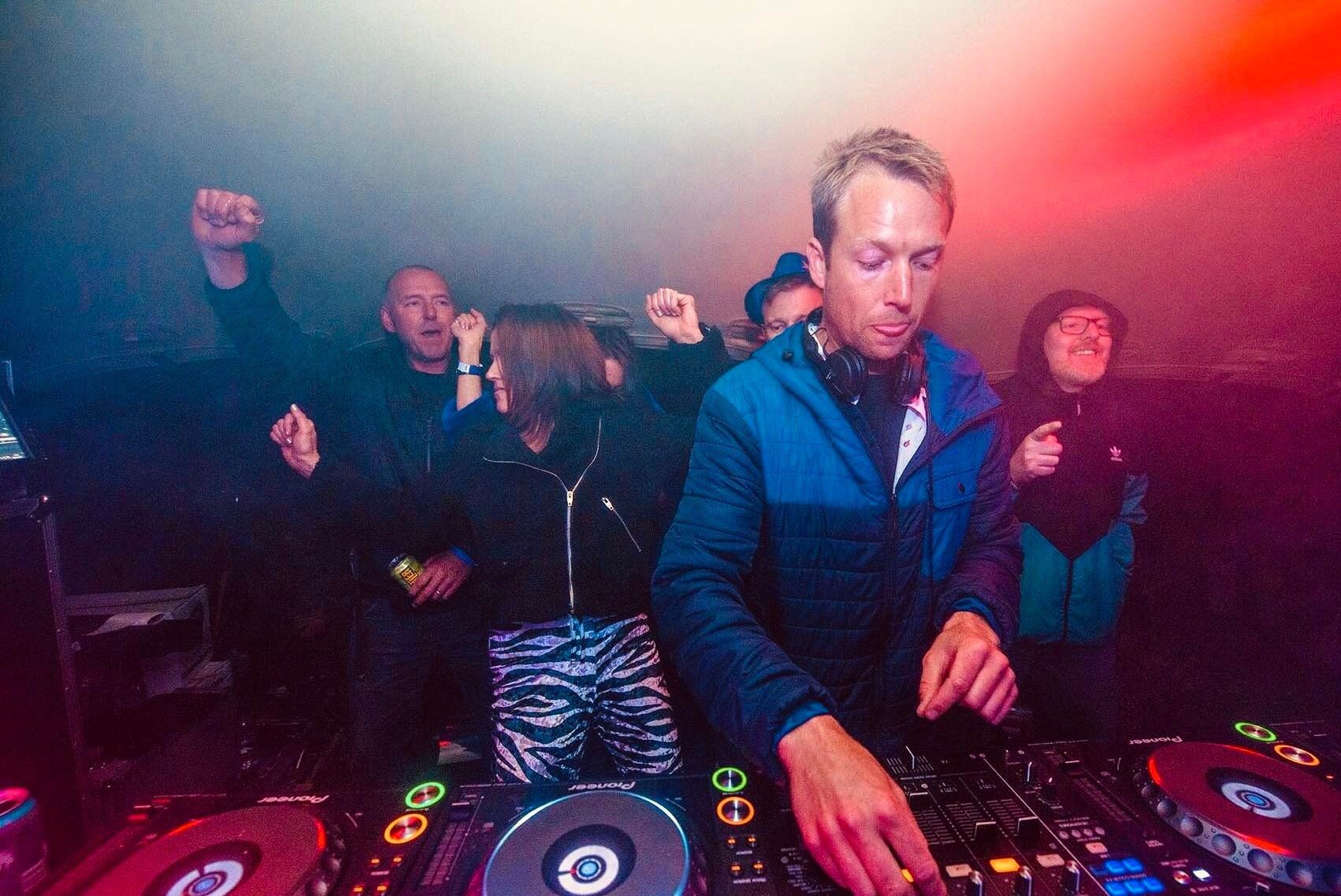 A man is playing music in front of a crowd at a party.