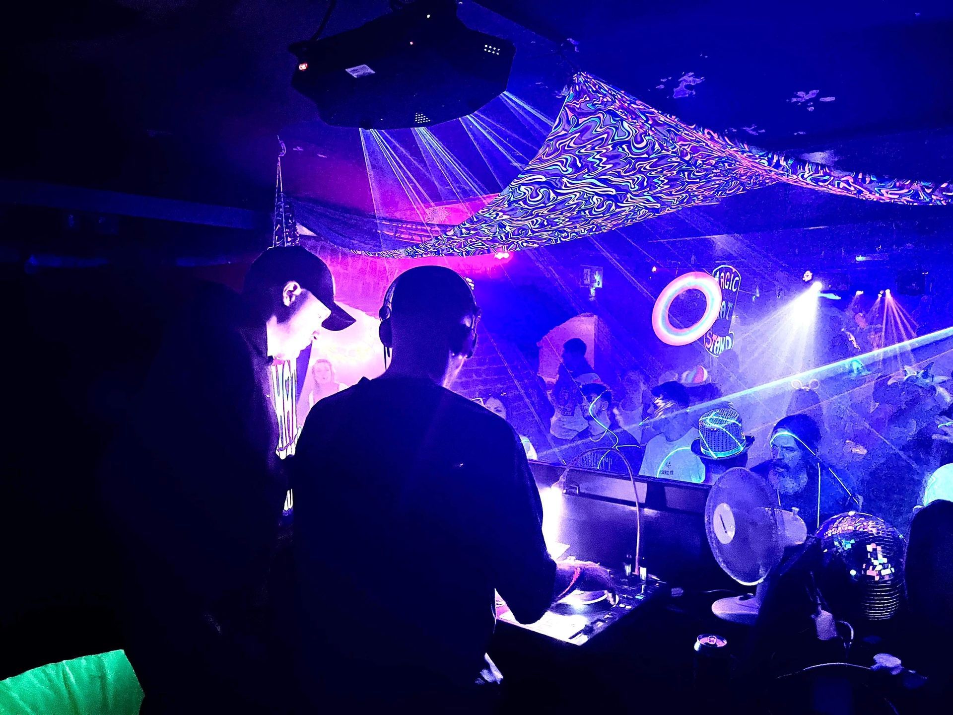 A group of people are standing in a dark room with purple lights.