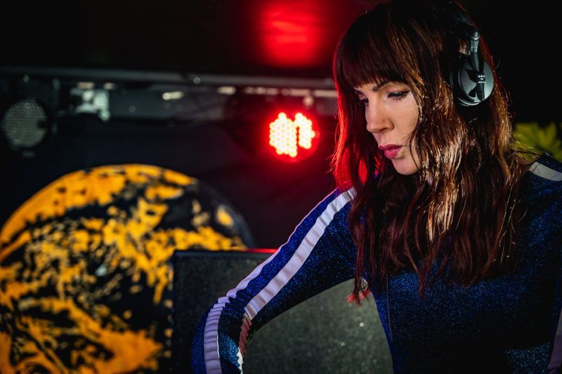 A woman wearing headphones is playing music on a stage.