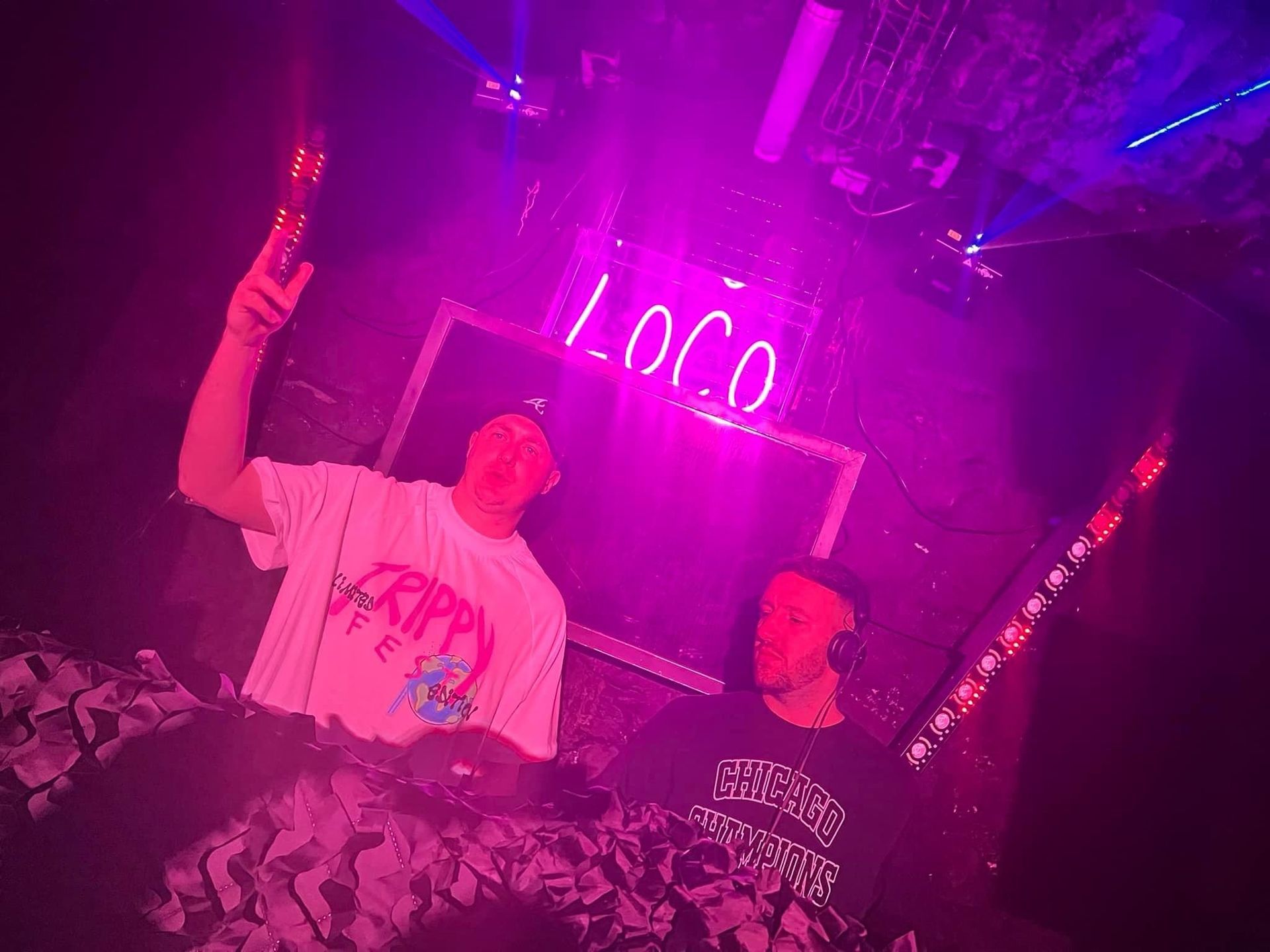 Two men are standing in front of a sign that says loco on it.