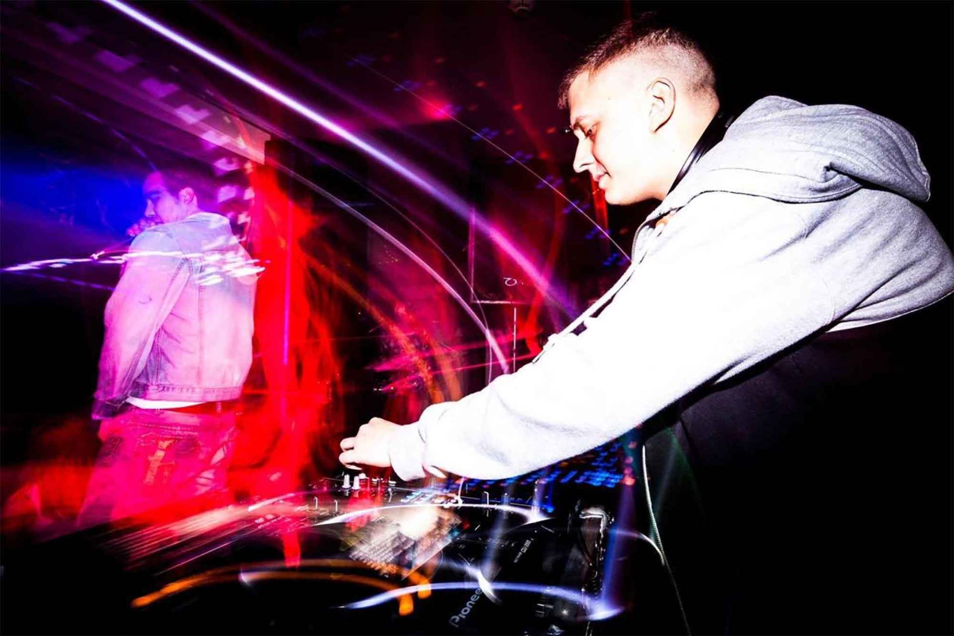 A man is playing a dj set in a dark room.