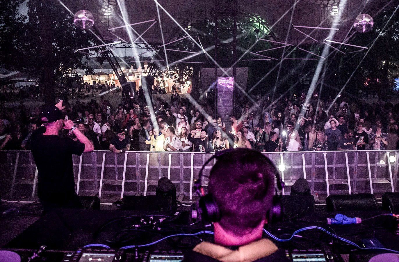 A man wearing headphones is sitting in front of a crowd at a concert.