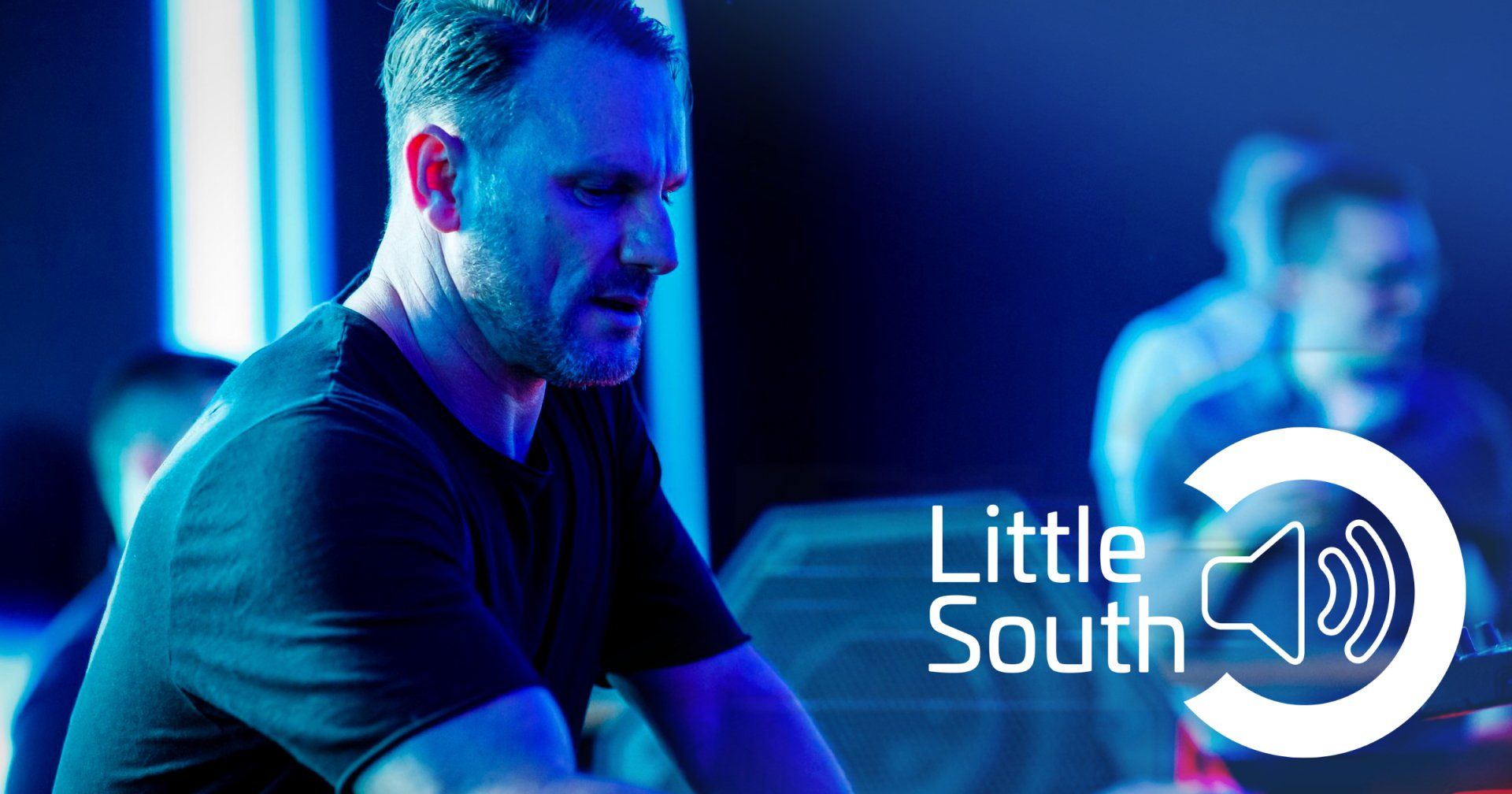 A man in a black shirt is sitting in front of a little south logo