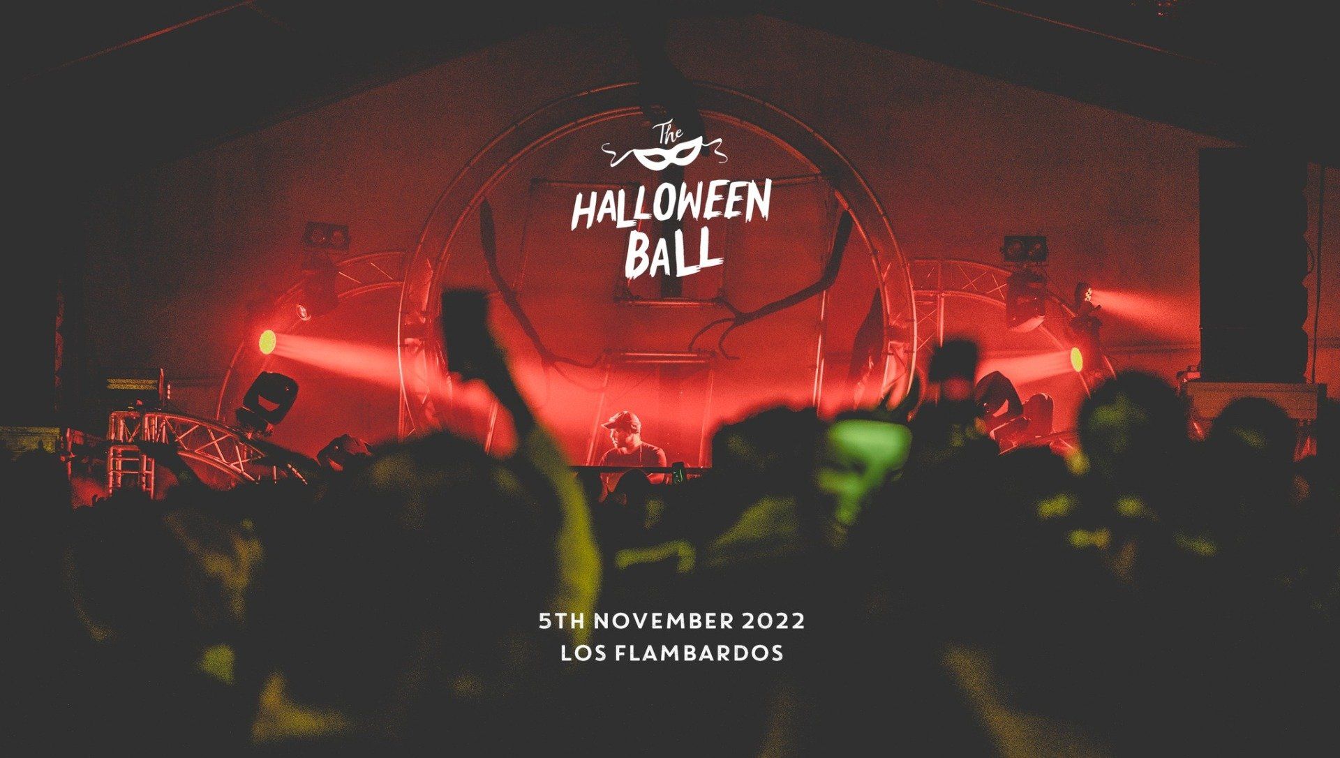 A crowd of people are standing in front of a stage at a halloween ball.
