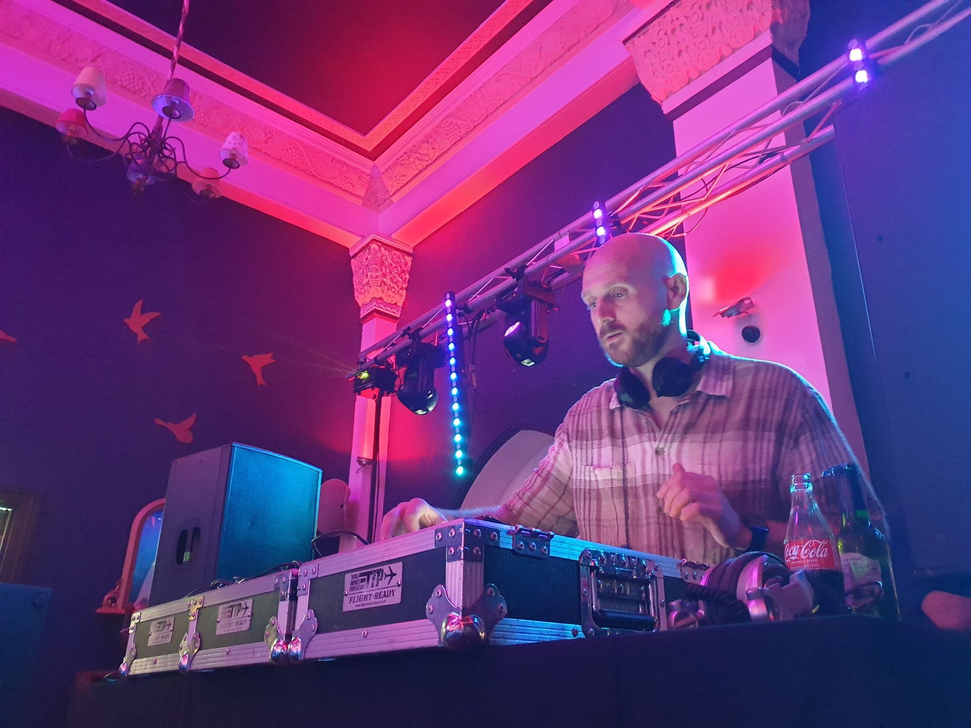 A man is playing a dj set in a dark room.