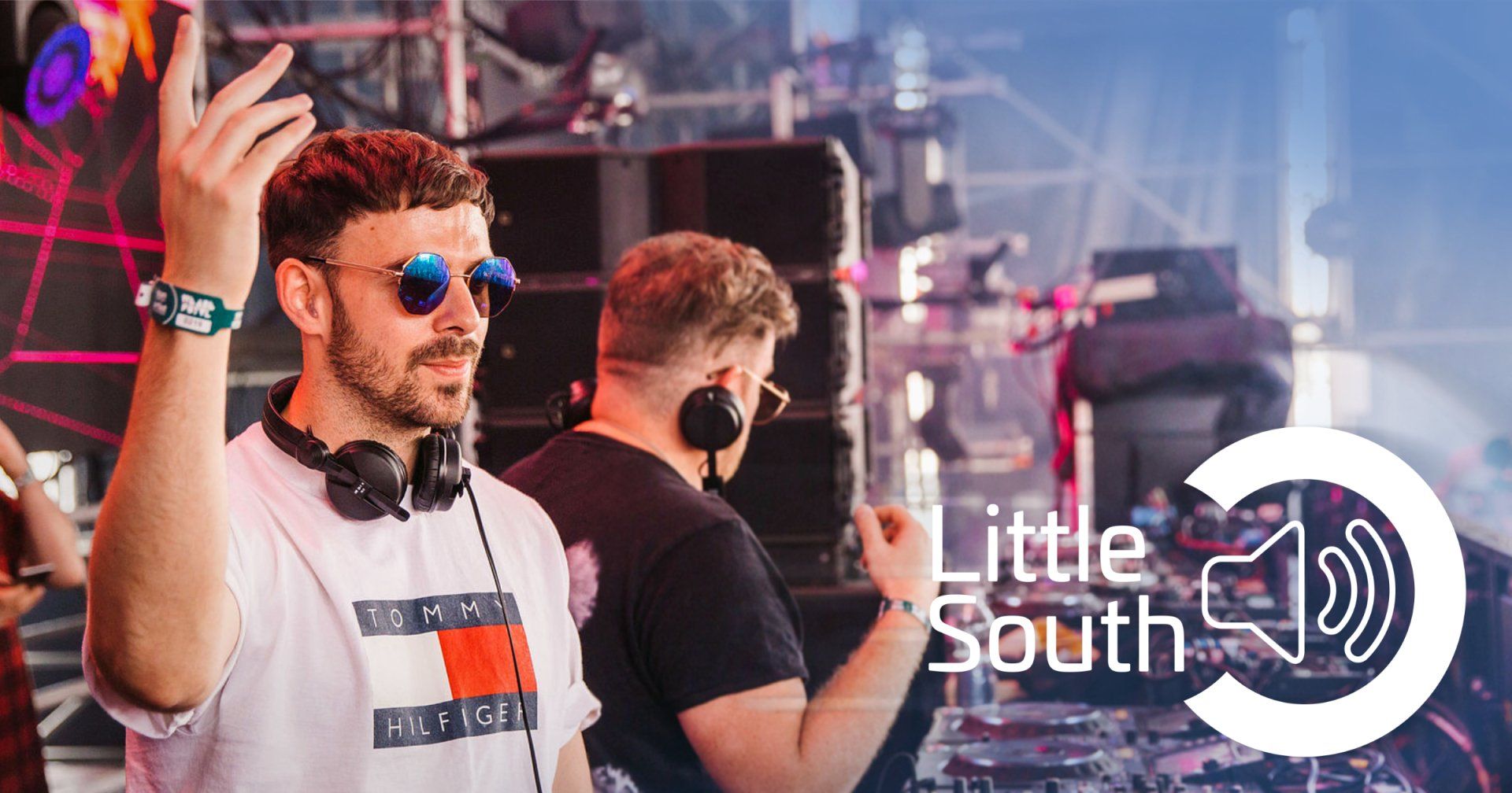 A man wearing headphones and sunglasses is standing on a stage.