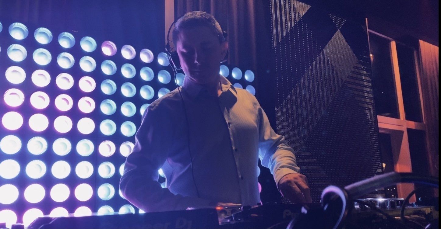 A man wearing headphones is playing music in a dark room