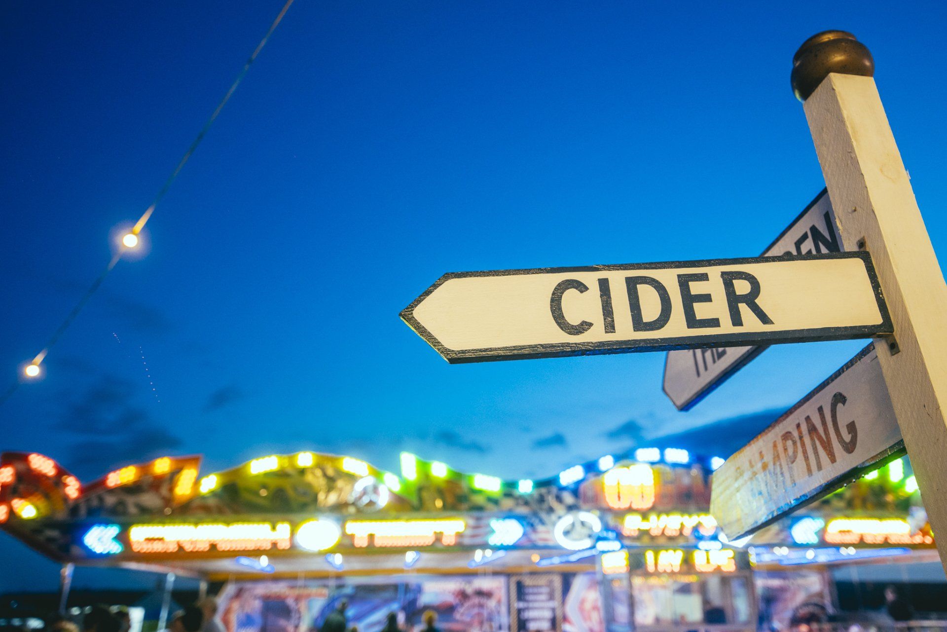 A sign that says cider is in front of a carnival ride.