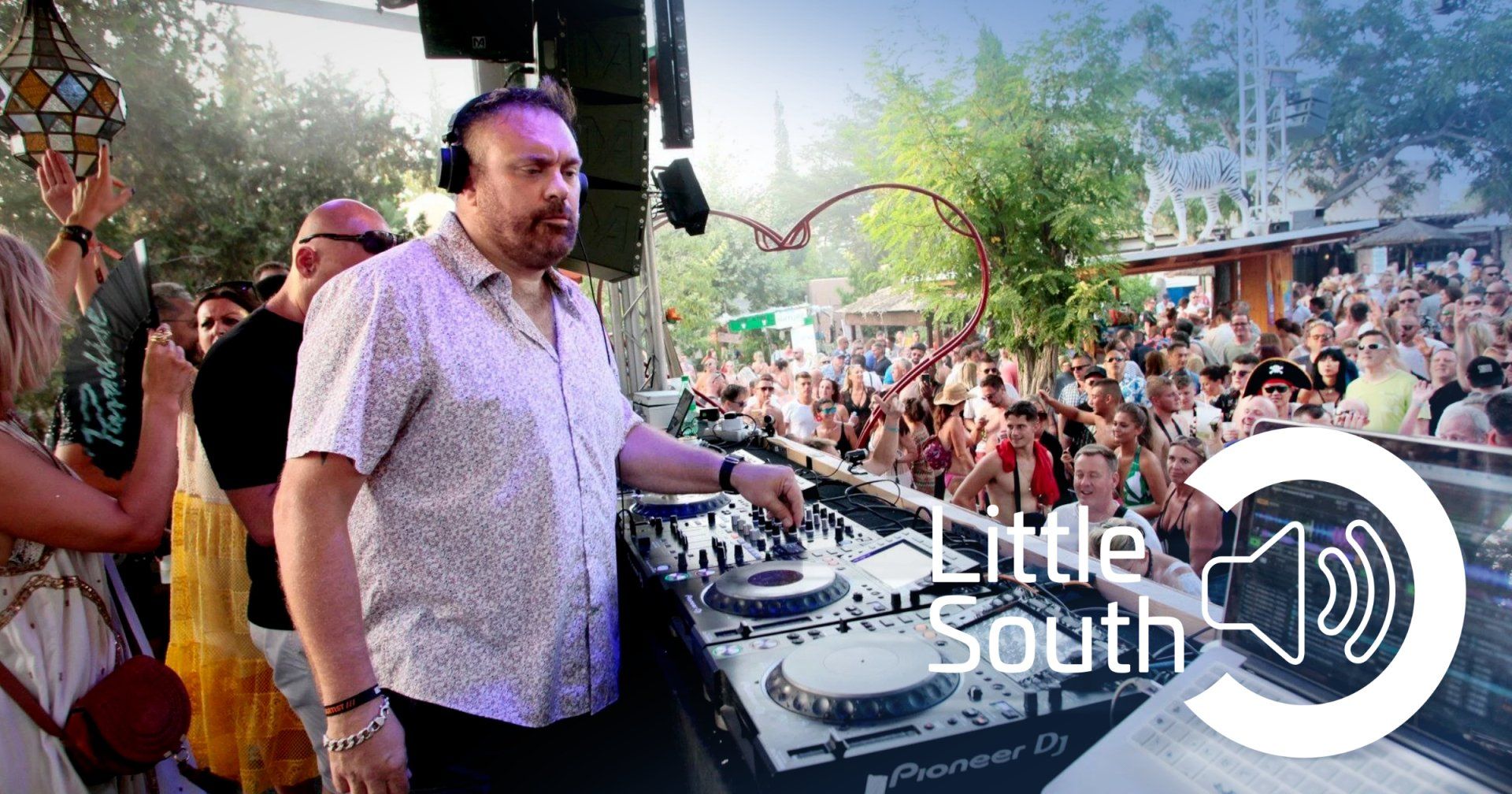 A man is playing a dj set in front of a crowd of people.
