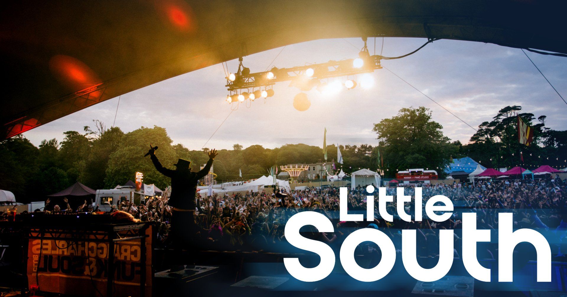 A man is standing on a stage in front of a crowd at a little south festival.