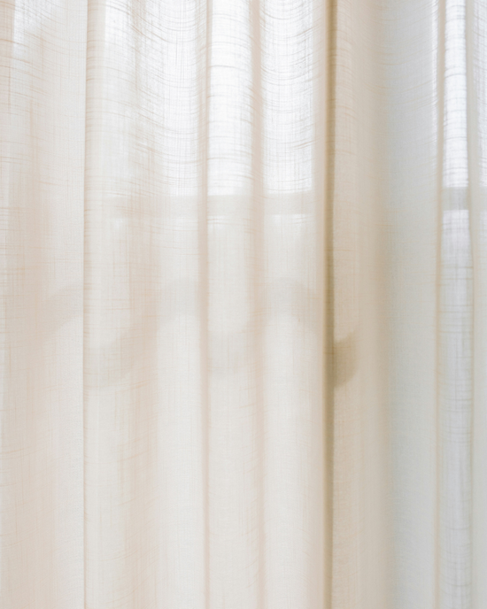 Cortinas transparentes de color beige con luz natural suave que se filtra a través de la ventana.