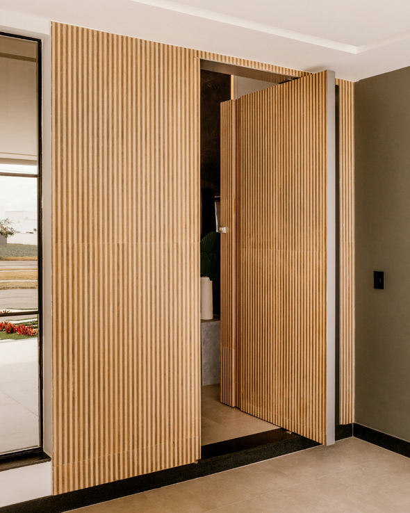 Separador de ambientes plegable de listones de madera parcialmente abierto en una puerta interior moderna.