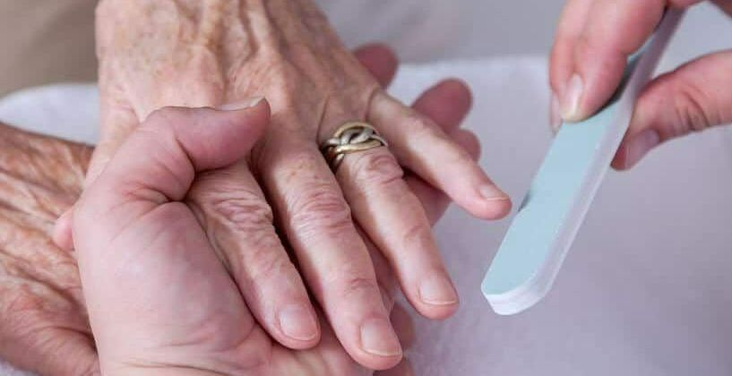 Professionele nagelverzorging en vijlen van de kwetsbare nagels van een oudere cliënt in de zorg.