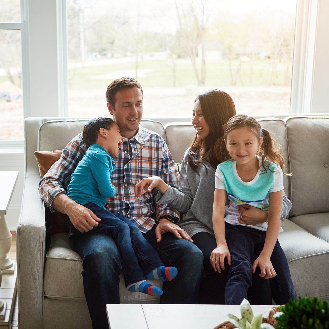 Family sitting on a couch, smiling and talking in a bright living room.