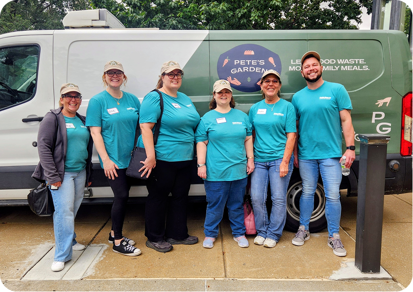 Six people in matching teal shirts and caps stand in a line before a branded green and white van, smiling for the camera.