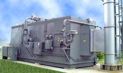 A large gray machine is sitting on top of a lush green field.