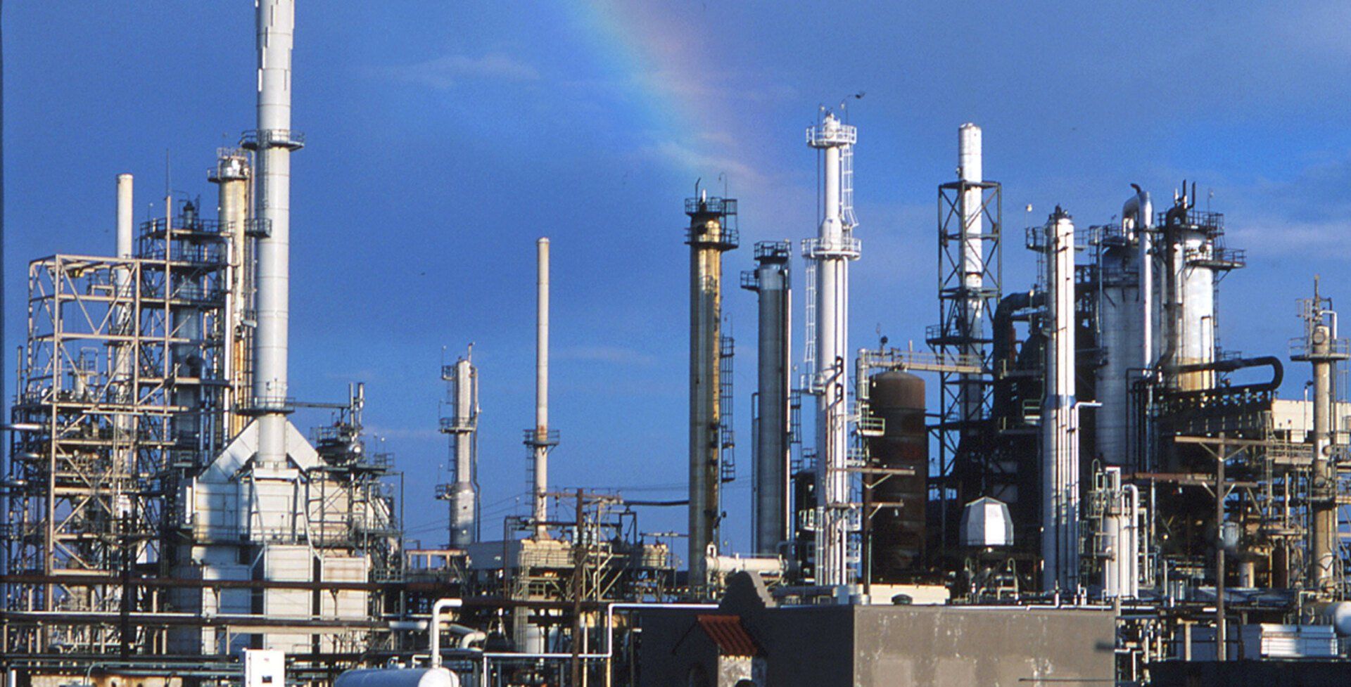 A large oil refinery with a rainbow in the sky