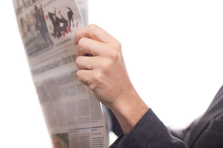 A person is reading a newspaper with a picture of people on it