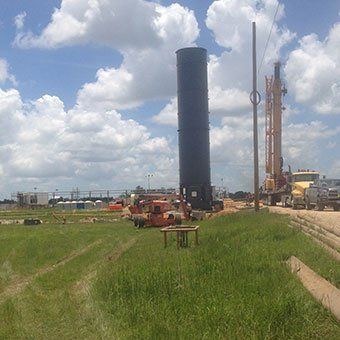 A large black tower is in the middle of a grassy field