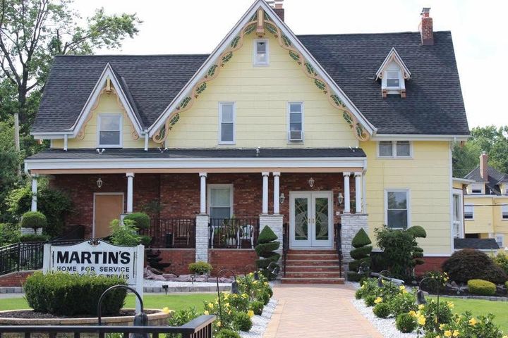 Yellow historic house with porch and a MARTINS realty sign in the front yard