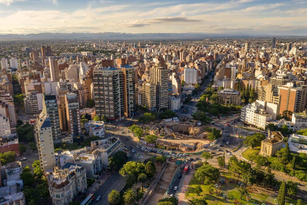 Vista aérea de um horizonte urbano denso com arranha-céus, ruas e um parque ao pôr do sol.