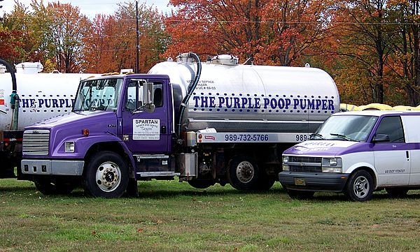 A purple and white vacuum truck labeled