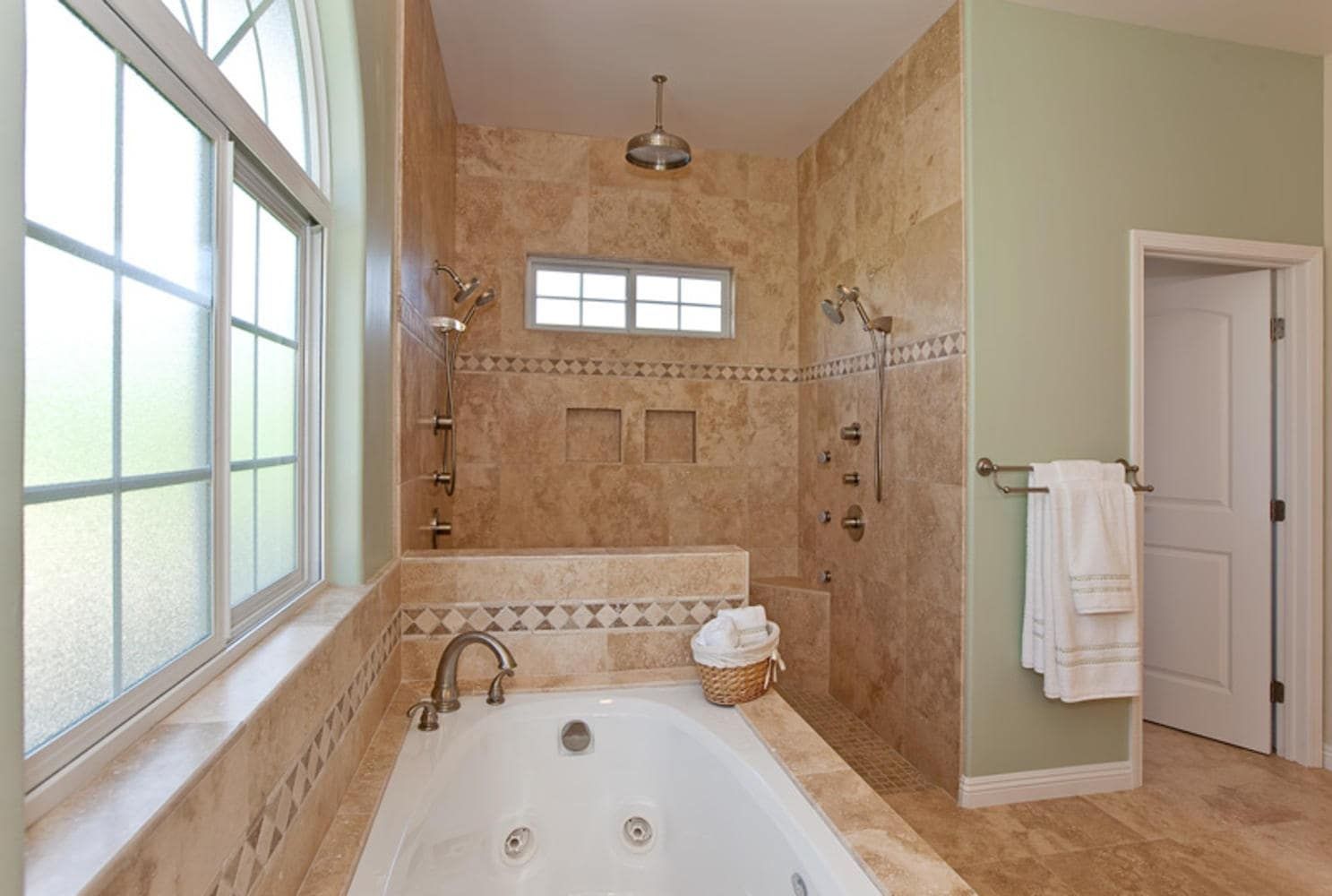 Bathroom with jacuzzi tub and tile shower. Beige tiles and mint-green walls.