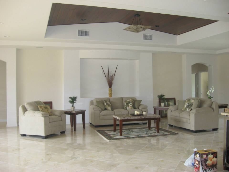 Living room with light beige couches and a rug on a marble floor; decorative plants.