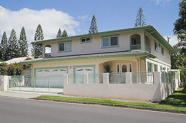 Two-story house with light pink exterior, green trim, and gated driveway.