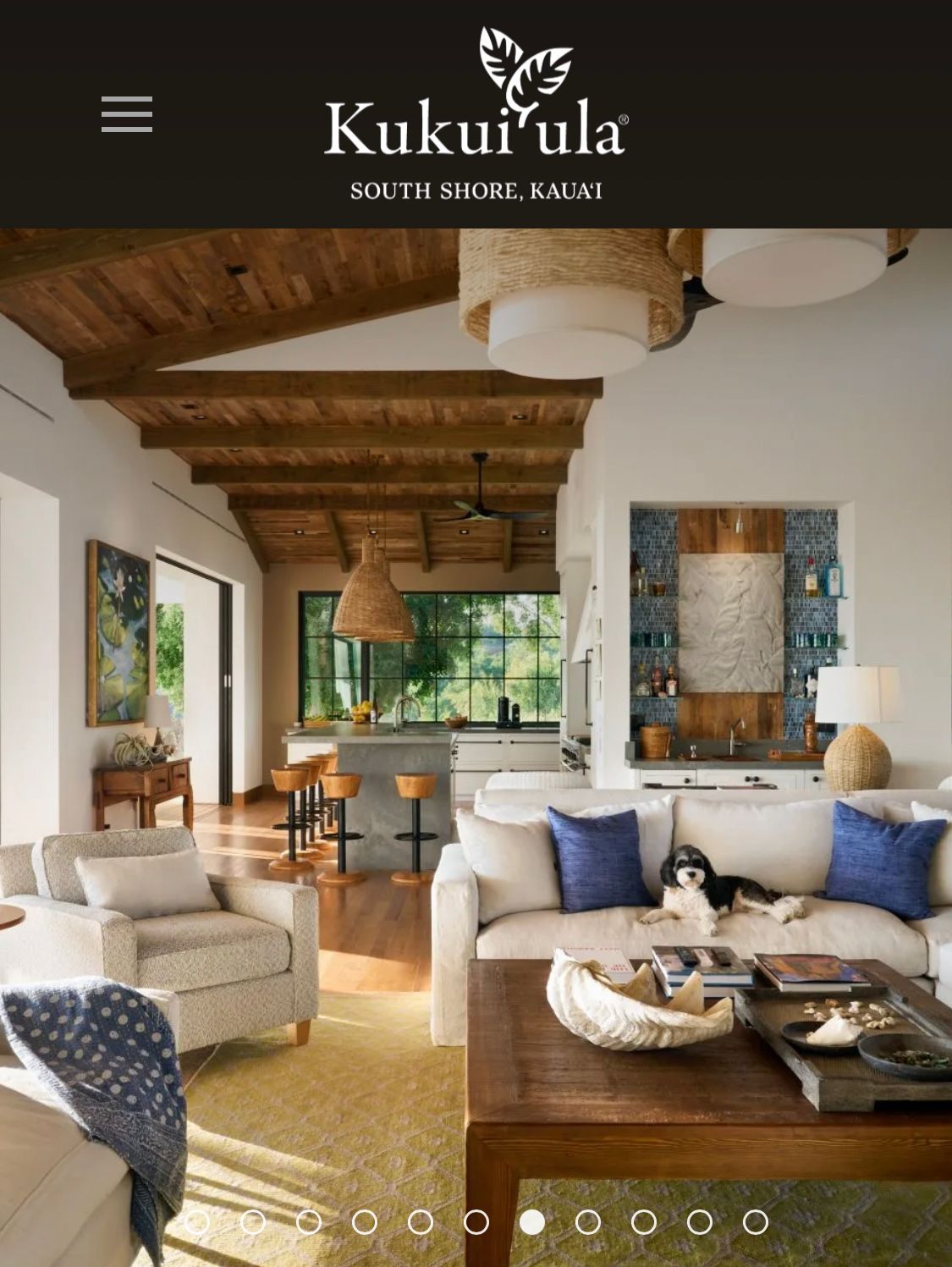 Interior of a spacious living room at Kukuʻula, with a dog on the couch and wood-beamed ceiling.