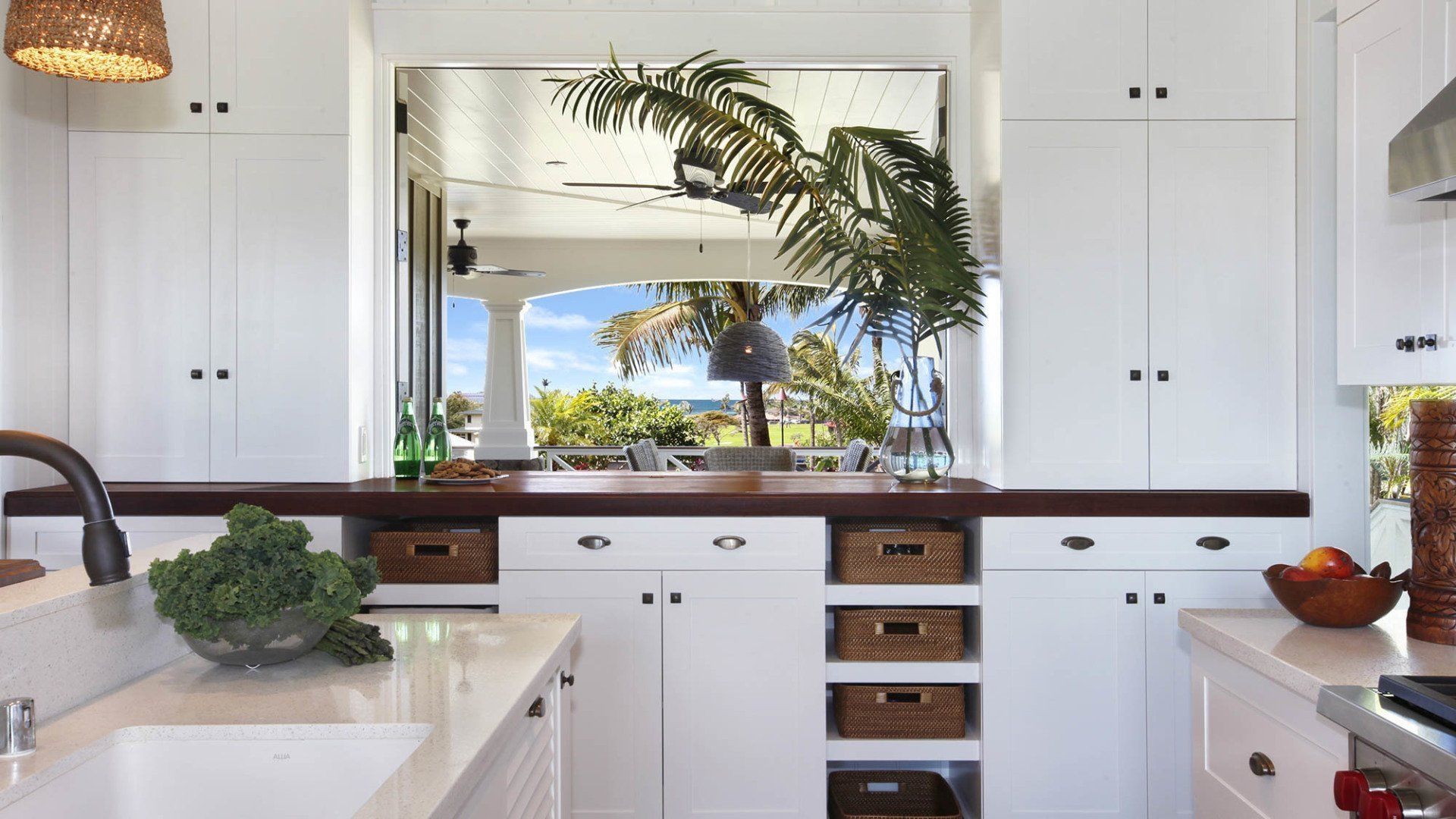 White kitchen with a view of an outdoor scene; cabinets, countertops, and a wooden backsplash.