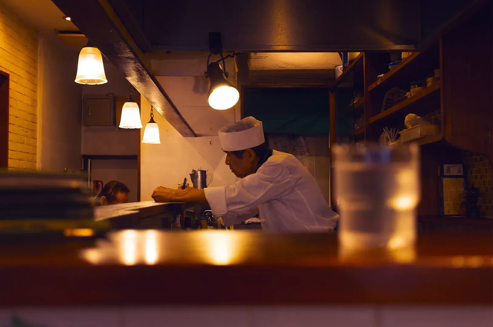 A focused chef working in a quiet, warmly lit kitchen, symbolizing the pursuit of mastery and how su