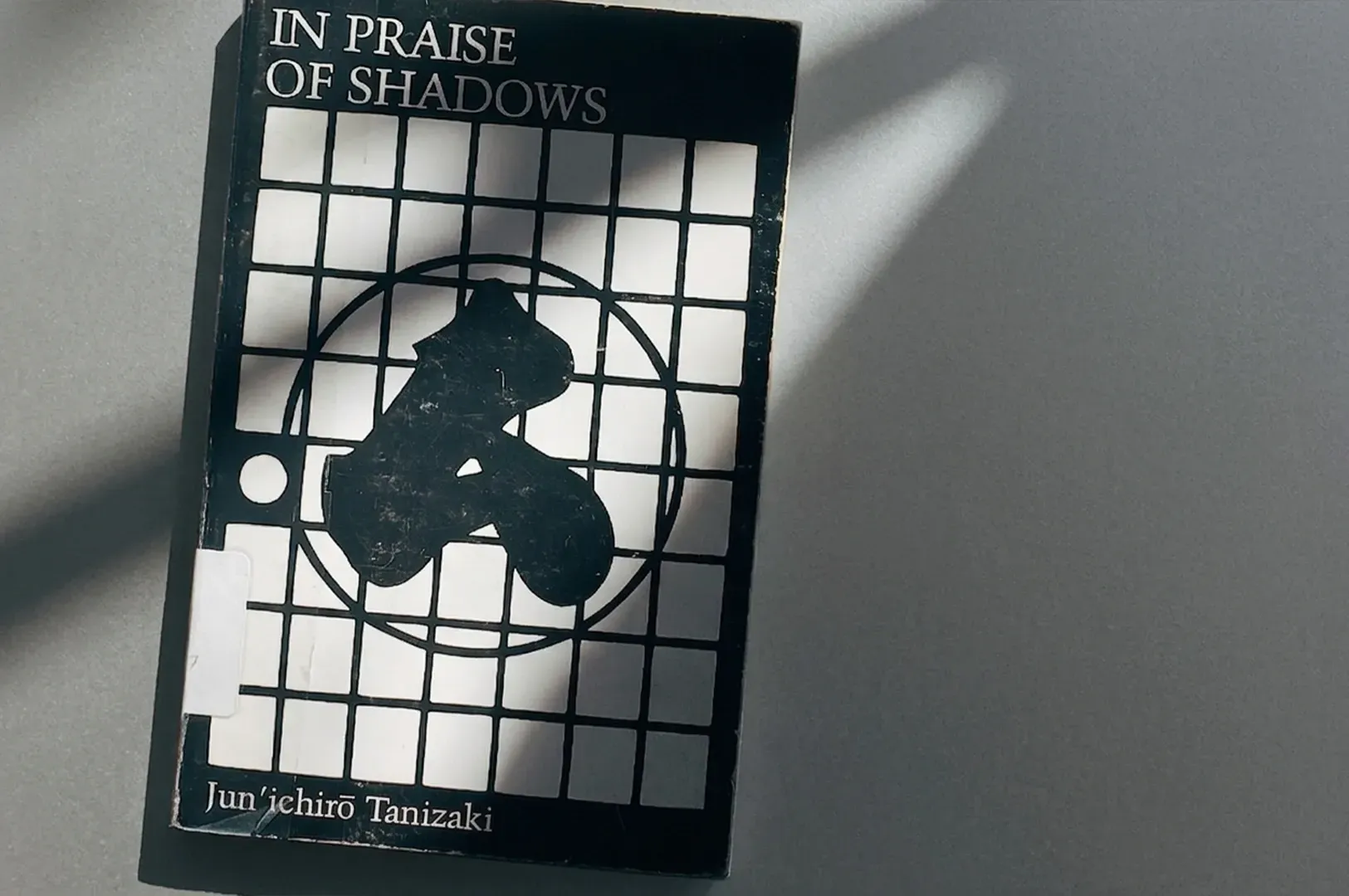 Book cover for In Praise of Shadows by Jun'ichirō Tanizaki, illuminated by a stark, contrasting beam