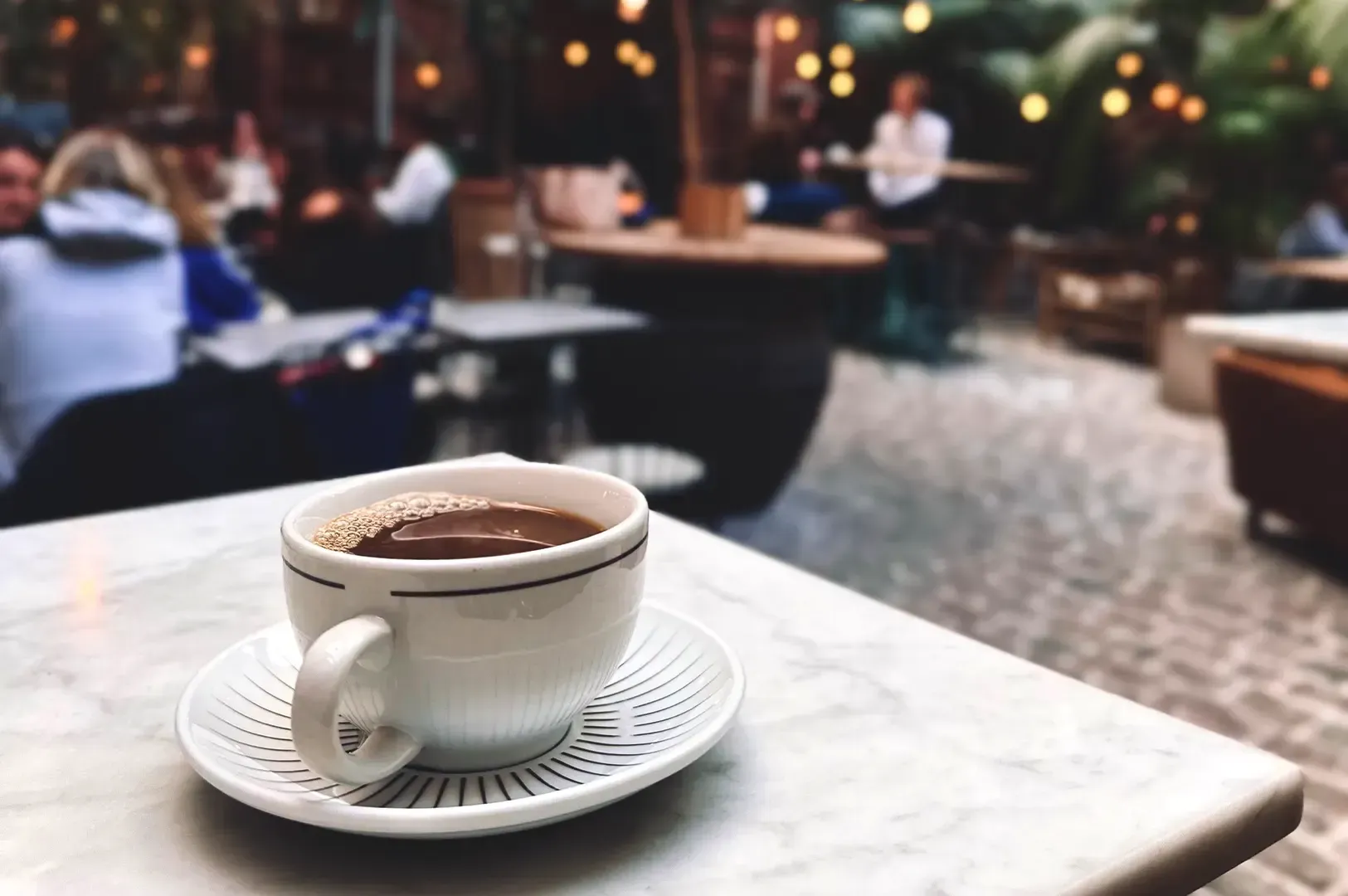 A cup of black coffee on a white marble table at an outdoor cafe, symbolizing quiet reflection on en