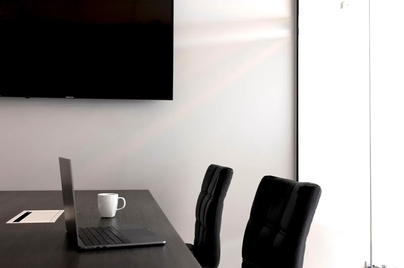 A quiet, minimalist office workspace featuring a laptop and mug, symbolizing the physical structure