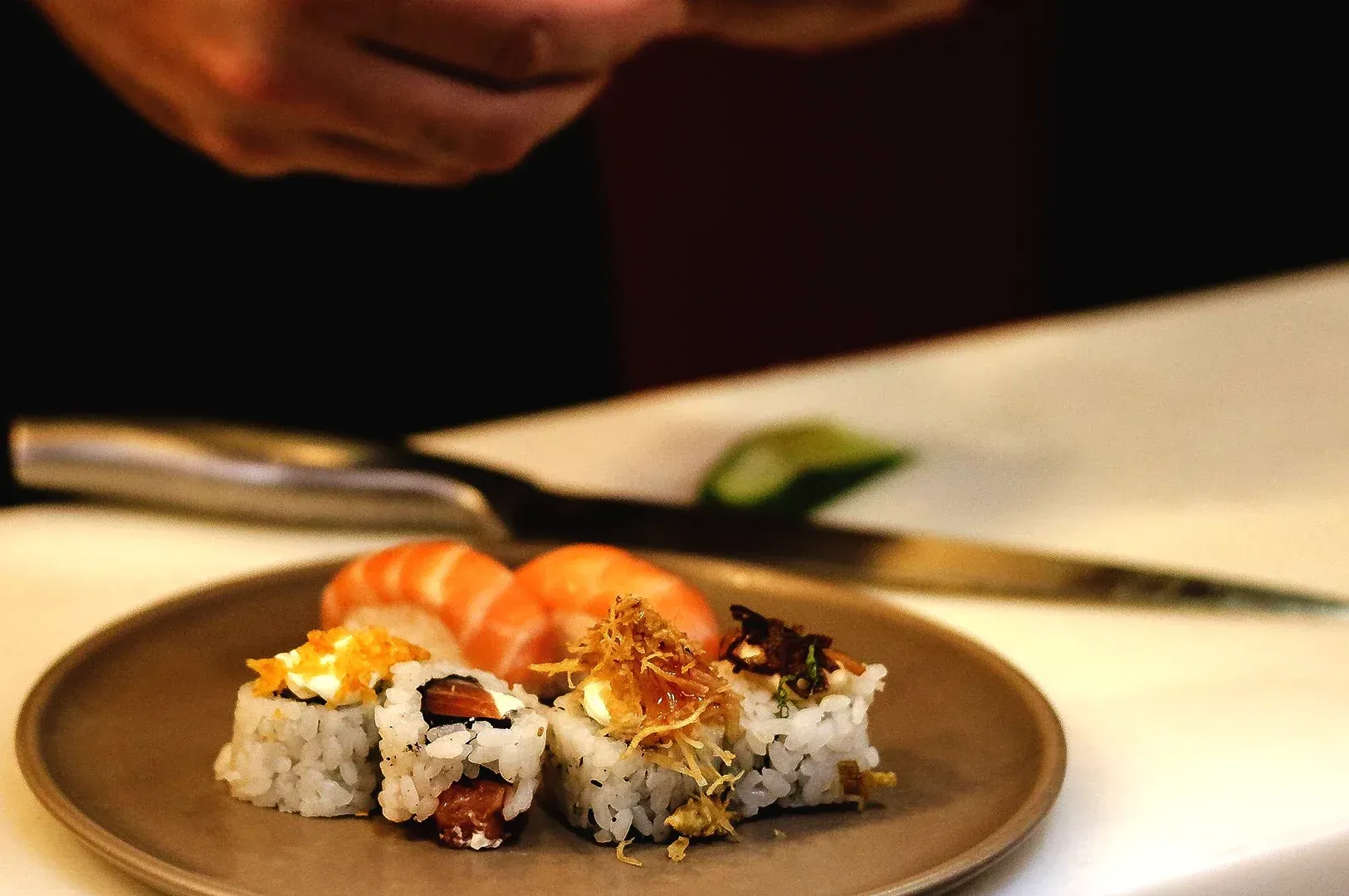 A close-up of a chef at an omakase meticulously preparing sushi rolls, highlighting the precision, c