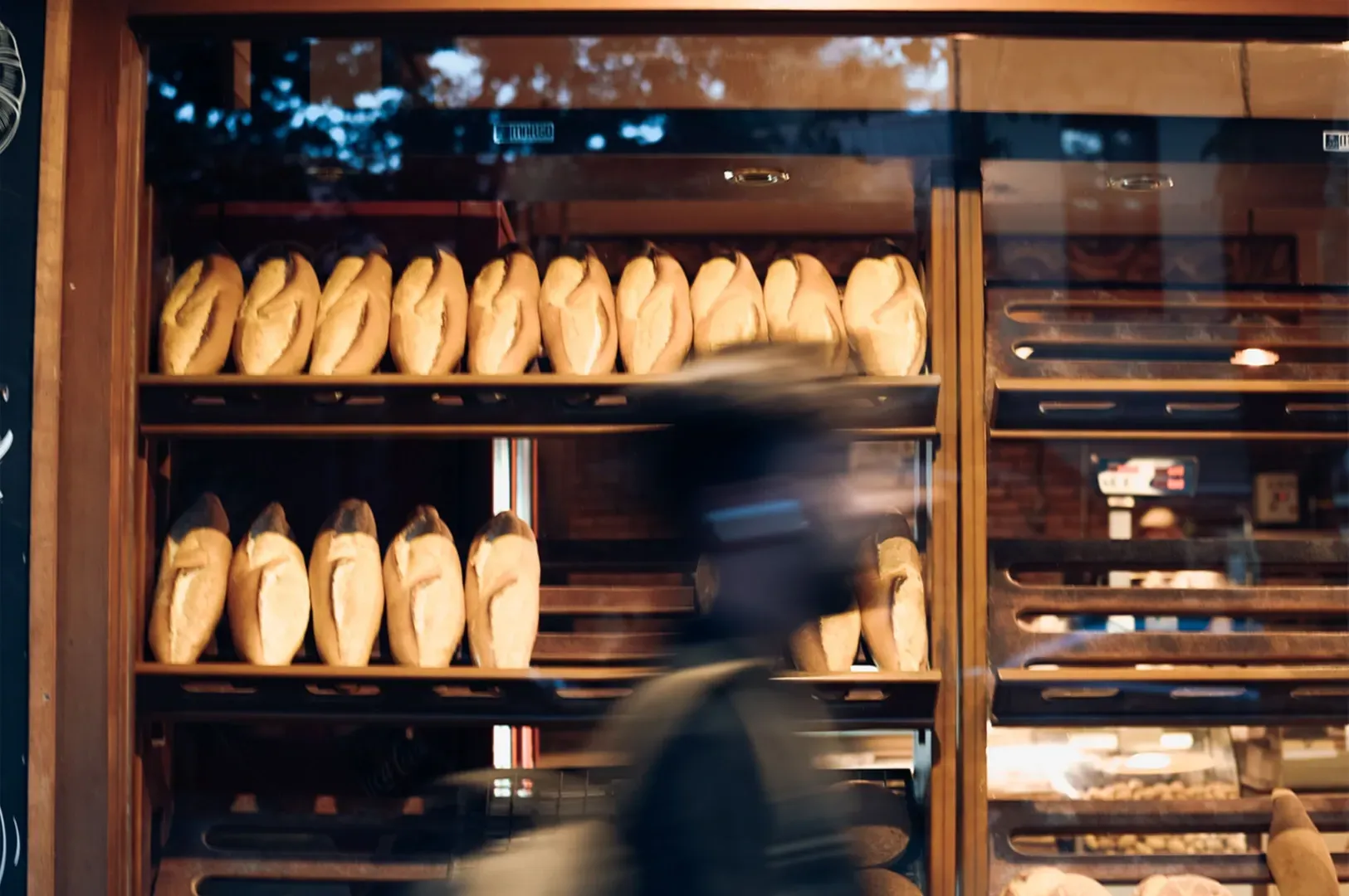 A candid photo of a person walking past a bakery window display, illustrating how slow, intentional 