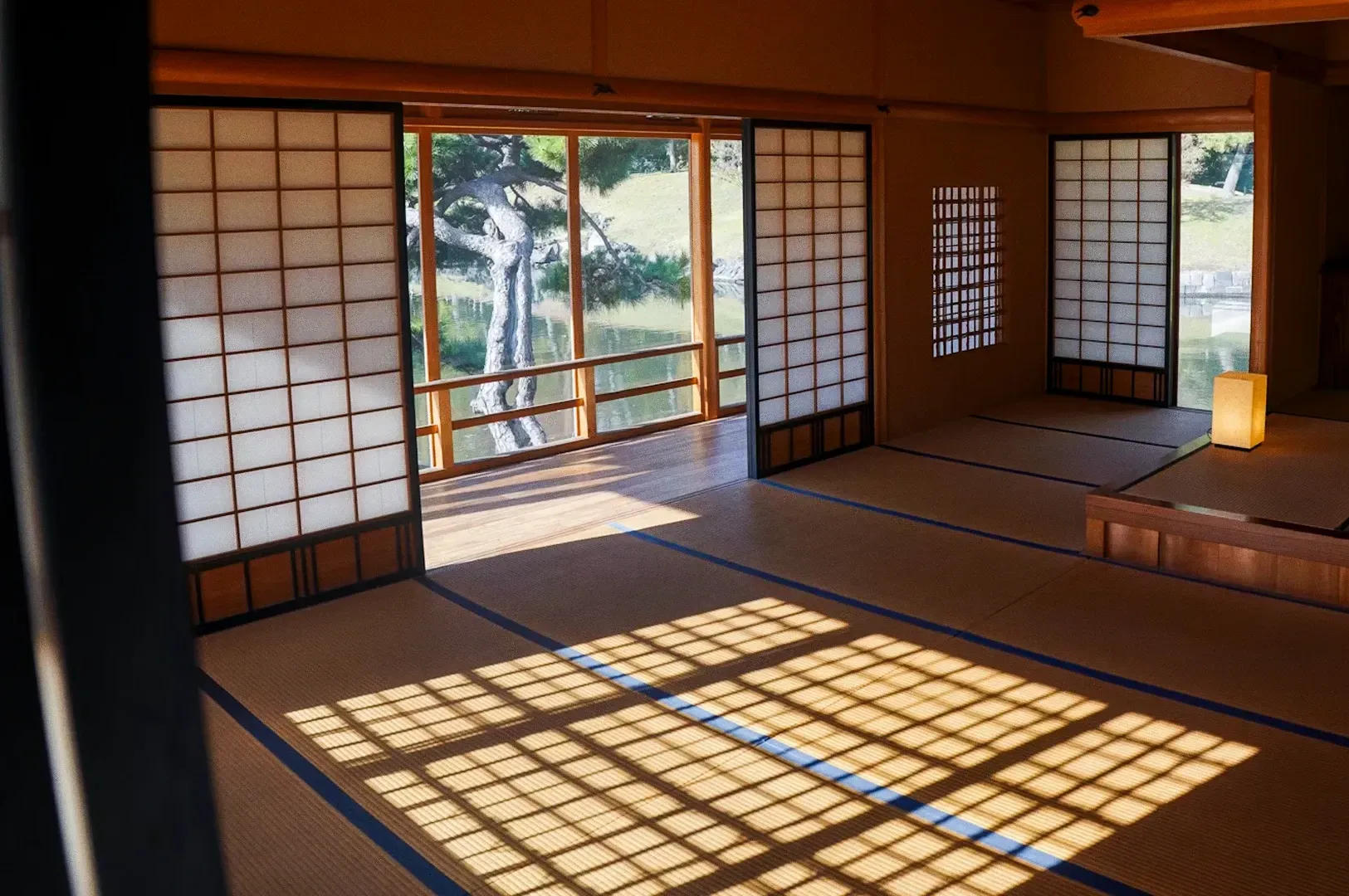 Wide-angle interior shot of minimalist Japanese tatami room with shoji screens and natural light cas