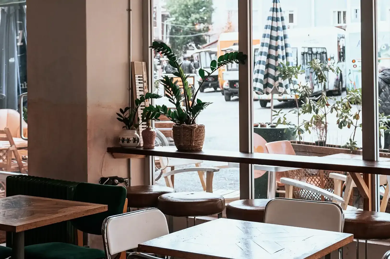 Quiet view looking out from a cozy cafe window at potted plants and passing street traffic, reflecting mindful observation in daily life.