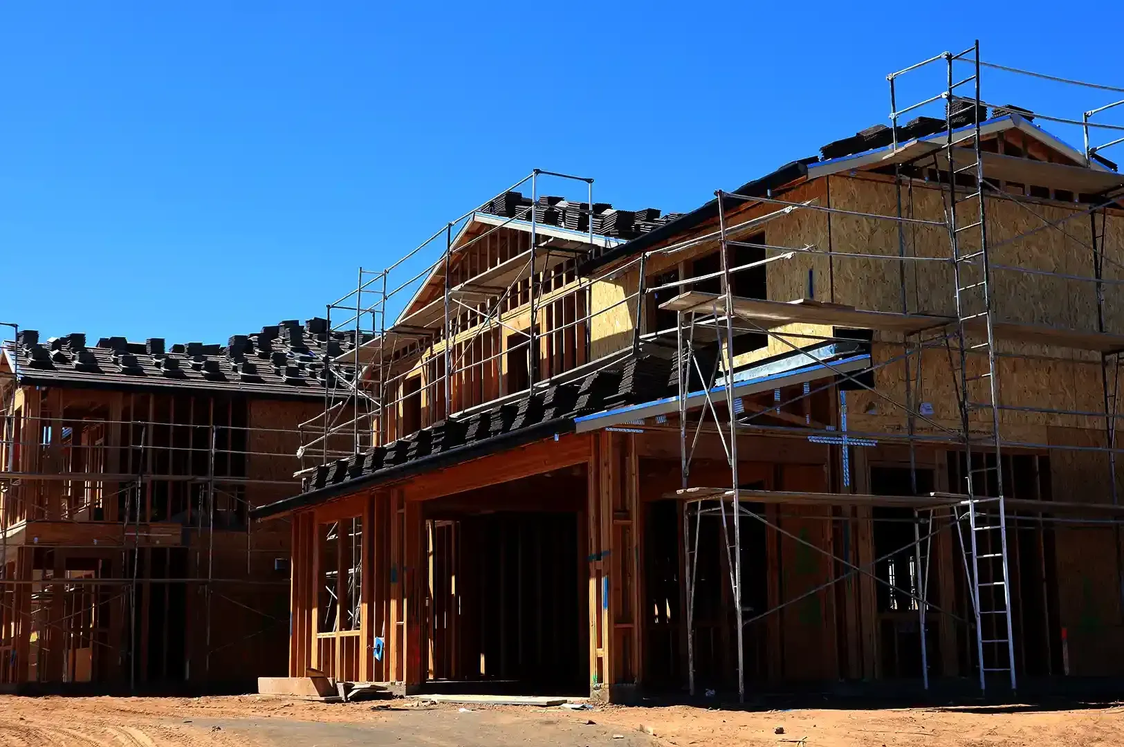 A residential building under construction surrounded by scaffolding, reflecting Christopher Alexander's architectural philosophy of creating structures with enduring depth and foundational aliveness.